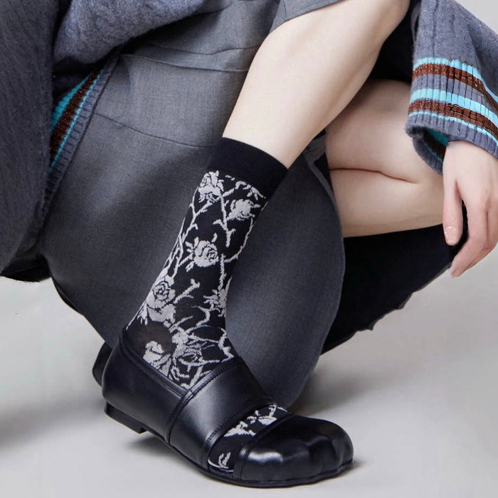 Model wearing a pair of black floral cotton socks, ideal for everyday outfits and sneakers.