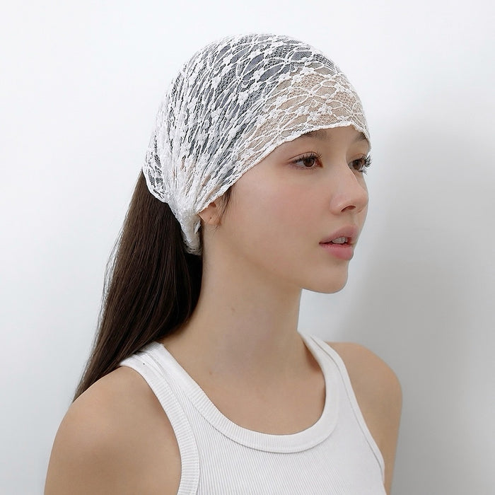 Three-quarter view of a model in a white tank top wearing the semi-sheer white floral lace headband.