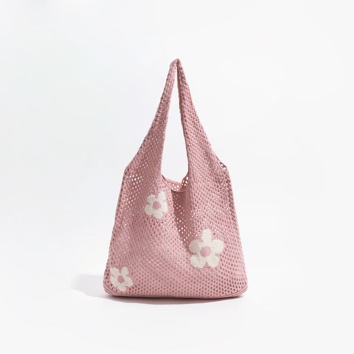 Angled view of Pink crochet shoulder bag with white flower details, made from blended knitting yarn,.