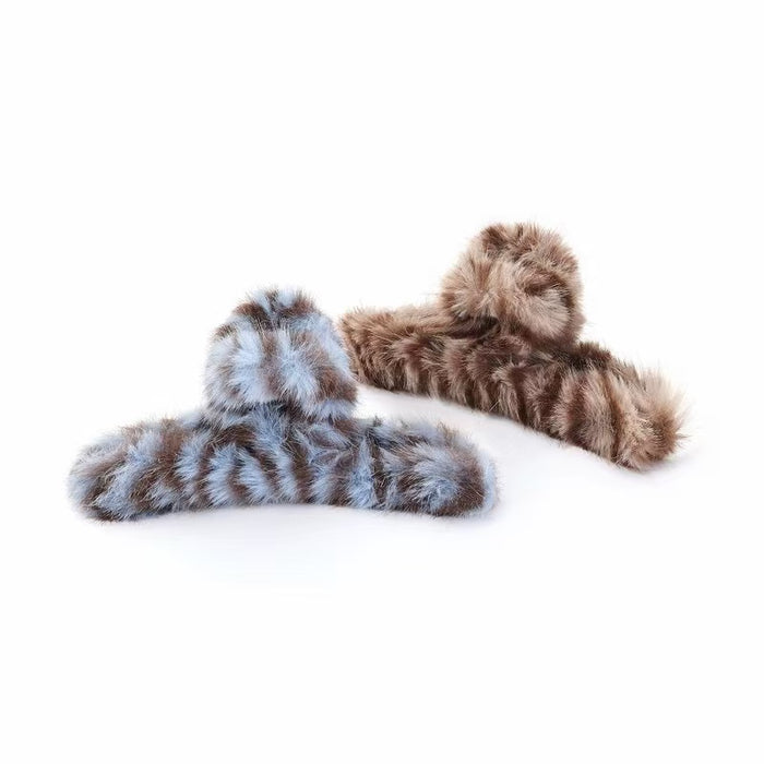 Front view of Two fluffy striped hair claws, one blue and one brown.