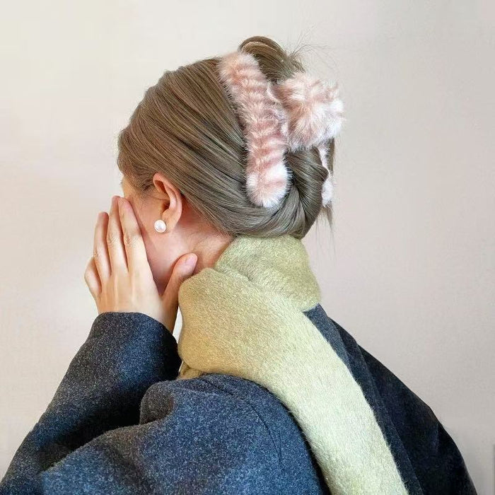 Model wearing a pink fluffy striped hair claw, easy for quick styling and photos.