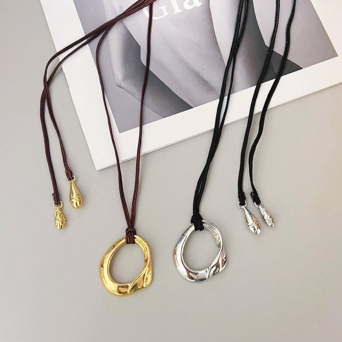 Flat lay of gold and silver fluid oval pendant necklaces showing leather cord details