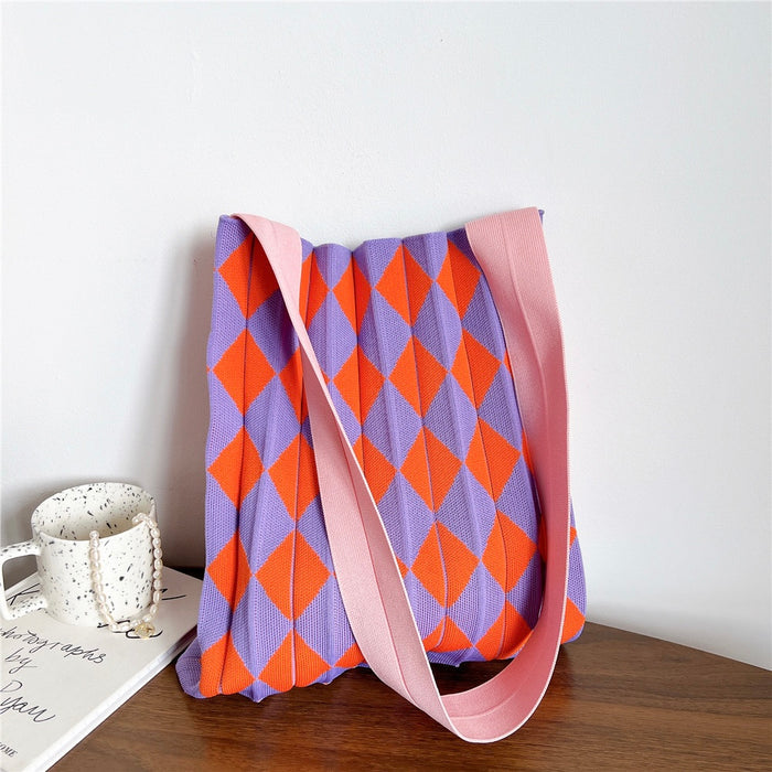 Close-up of a purple and orange argyle knitted tote bag with a pink shoulder strap.