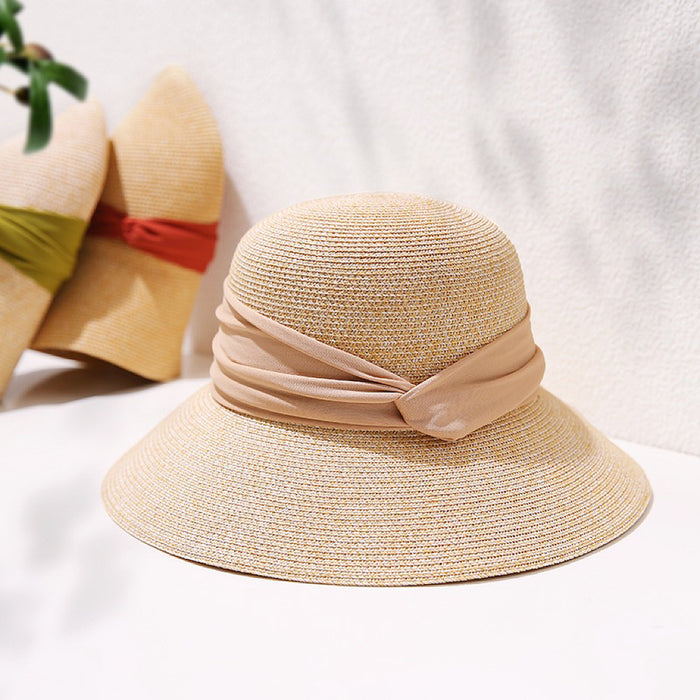 Foldable elegant straw hat with a wide brim and beige ribbon band for sophisticated summer sun protection.