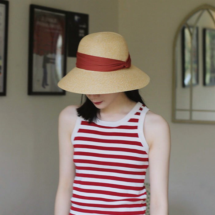 Model wearing red Ribbon Straw Hat. Bold vibrant shade featuring a secure and stylish ribbon chin tie.