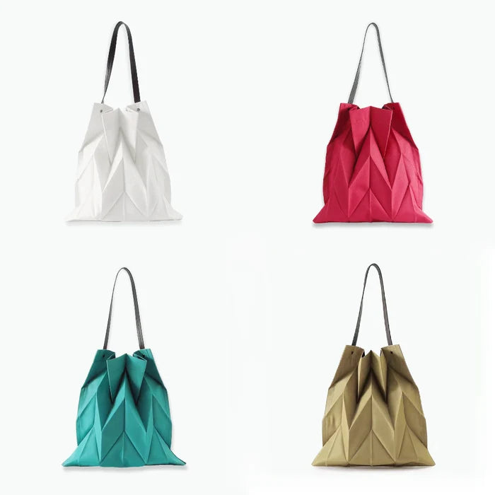 Four foldable canvas pleated shopper bags in white, red, peacock blue, and khaki with dark straps.