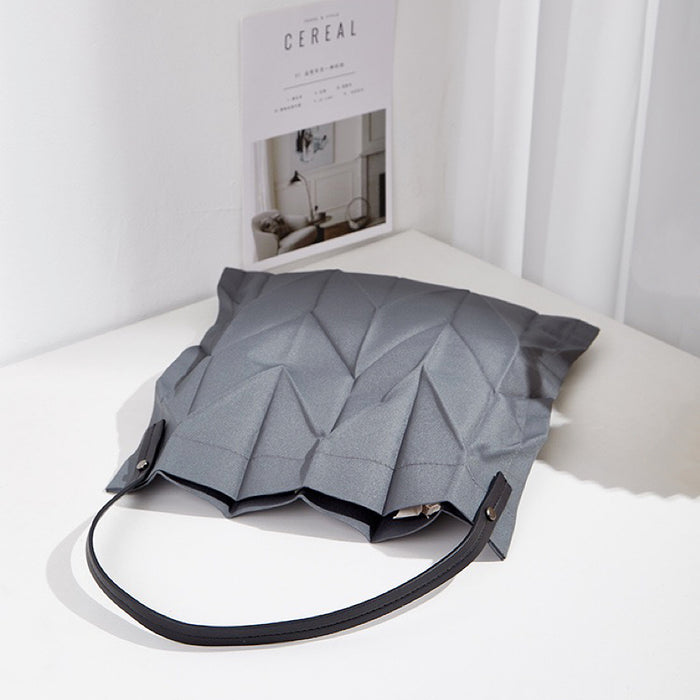 Grey pleated shopper bag resting on a table; modern minimalist aesthetic suited for office and daily commutes.