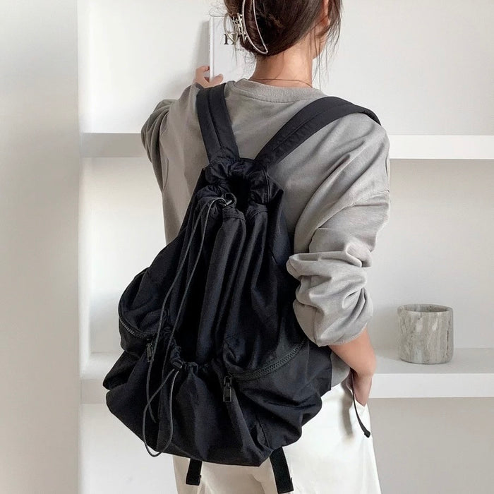 Model wearing black foldable backpack made of waterproof polyester, perfect for urban utility style.