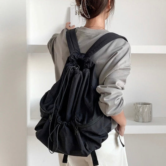 Model wearing black foldable backpack made of waterproof polyester, perfect for urban utility style.