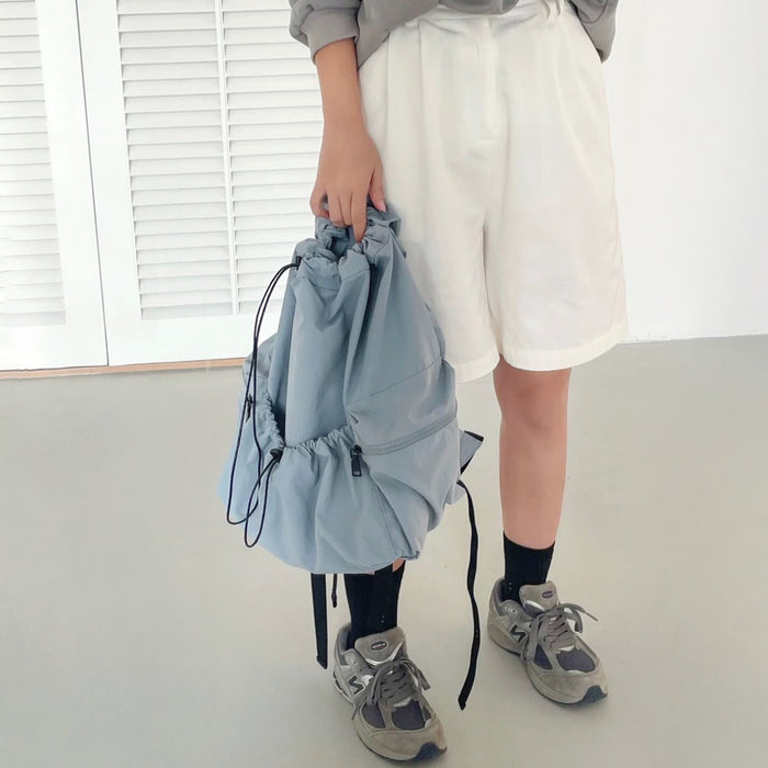 Model holding the blue foldable backpack made of waterproof polyester, perfect for urban utility style.