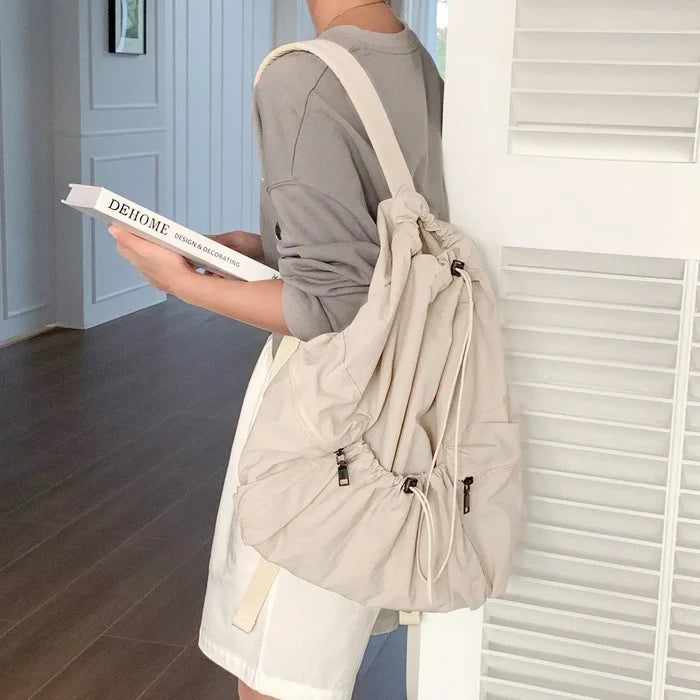 Model wearing beige foldable backpack featuring ultralight polyester and secure drawstring storage.