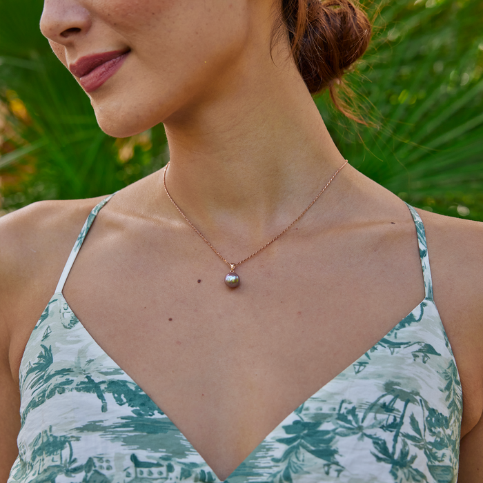 Close-up of a woman wearing a lilac freshwater pearl pendant in rose gold.