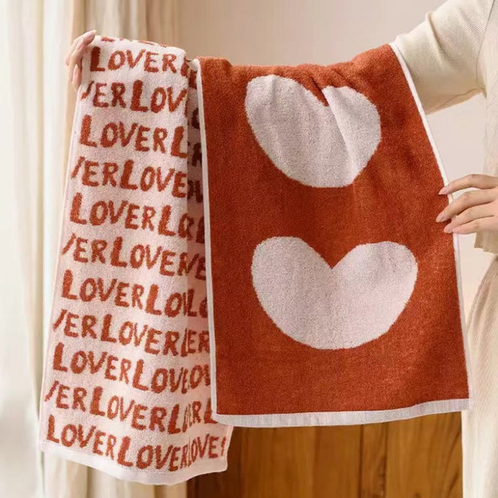Model holding two face towels with Lover text and large heart patterns separately.