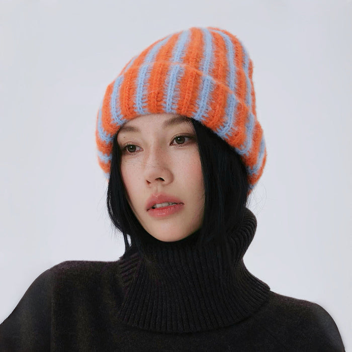 Model wearing a vibrant orange and blue fuzzy contrast striped beanie.