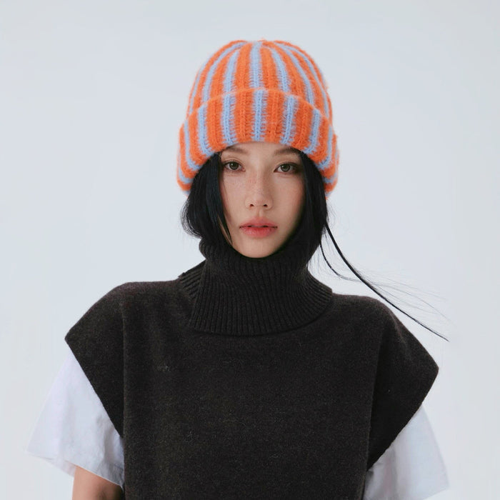 Frontal view of a model in a dark vest wearing the orange blue striped beanie.