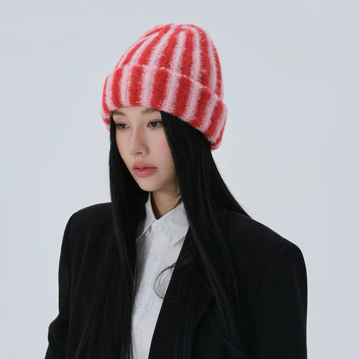 Side profile of the model wearing the red and pink striped knit beanie.