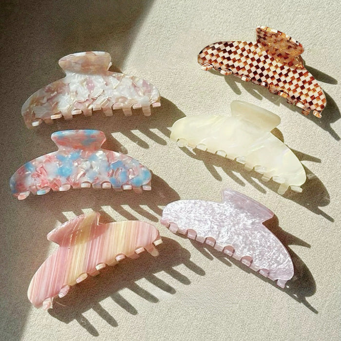 Flat lay of six Gentle Curve hair claws in assorted colors and patterns.