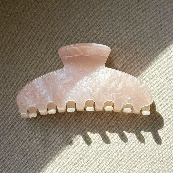 Flat lay of Gentle Curve  hair claw with soft glow color, great for everyday.