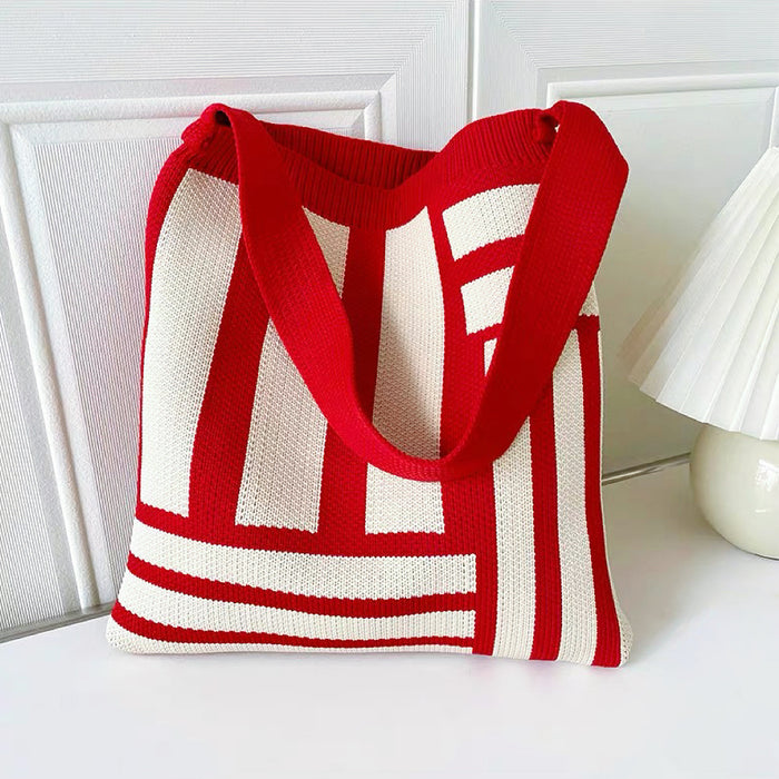 Angled view of Red and white geometric line knitted bag with elastic shoulder strap and open top.