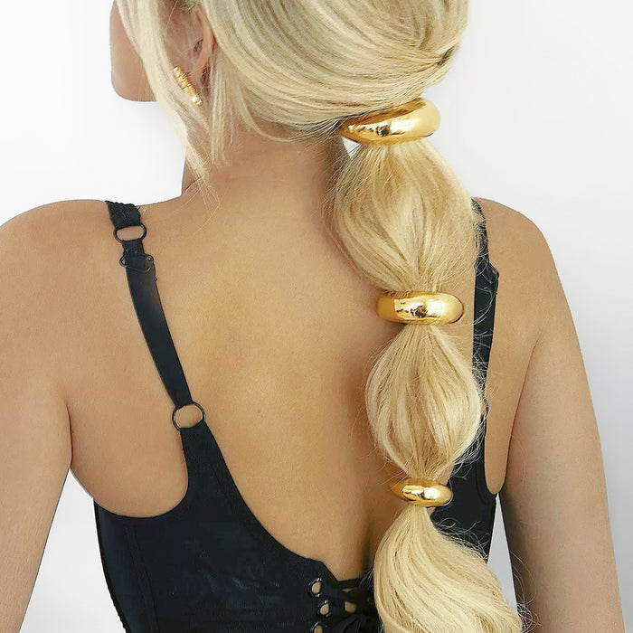 Blonde hair styled with three shiny gold stainless steel Gleaming Curve Hair Cuffs.