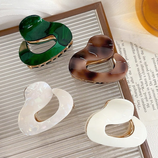 Front view of Four glossy acrylic cloud hair claws in dark green, brown,pure white, and white luster.