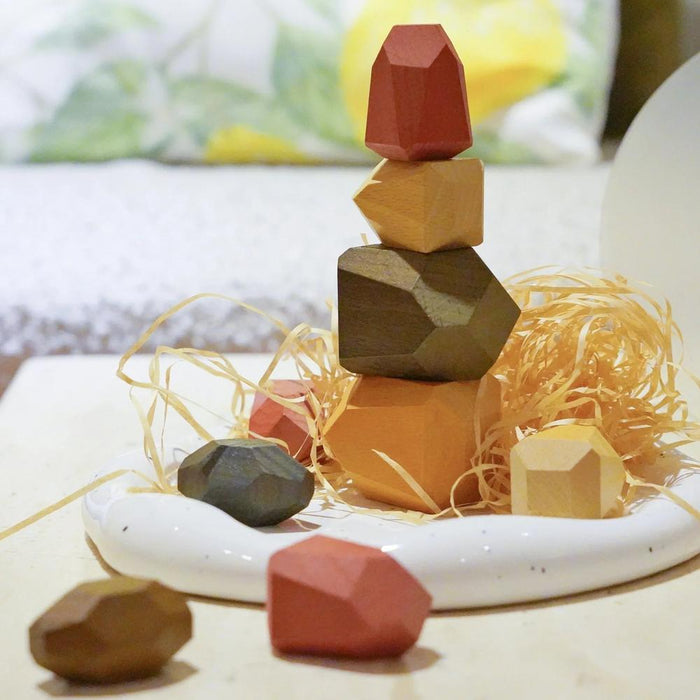 Angled view of Stacked wooden geometric blocks in natural colors on a tray.