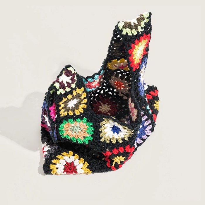 Close-up of Handmade black crochet flower grid bag with colorful floral granny squares .