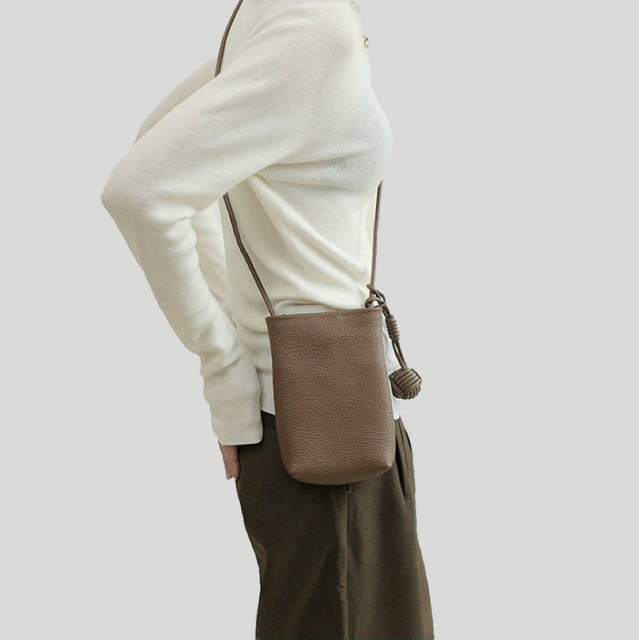 Model carrying a brown  hanging ball leather crossbody bag, ideal for city walks and gifting.