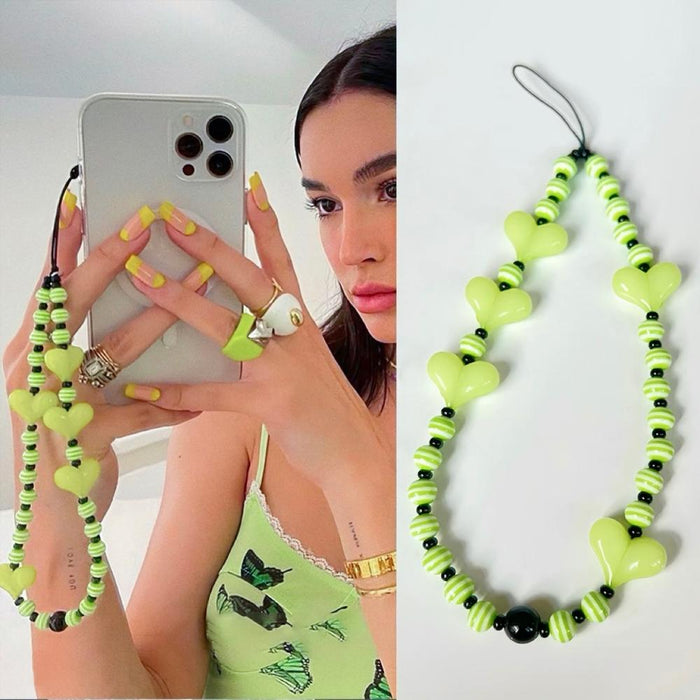 Model grabing a phone with lime green heart beat phone charm.