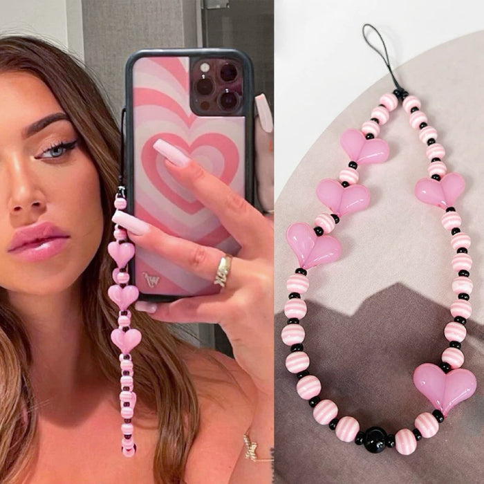 Model grabing a phone with pink heart beat phone charm.
