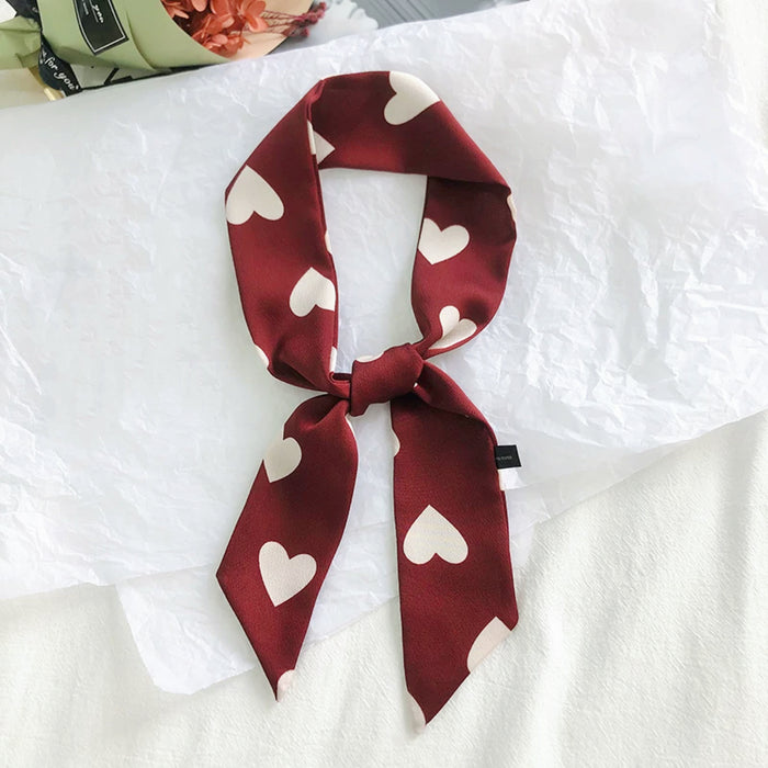 Front view of Red polyester skinny scarf with white heart pattern, tied in a knot in burgundy, great for office.