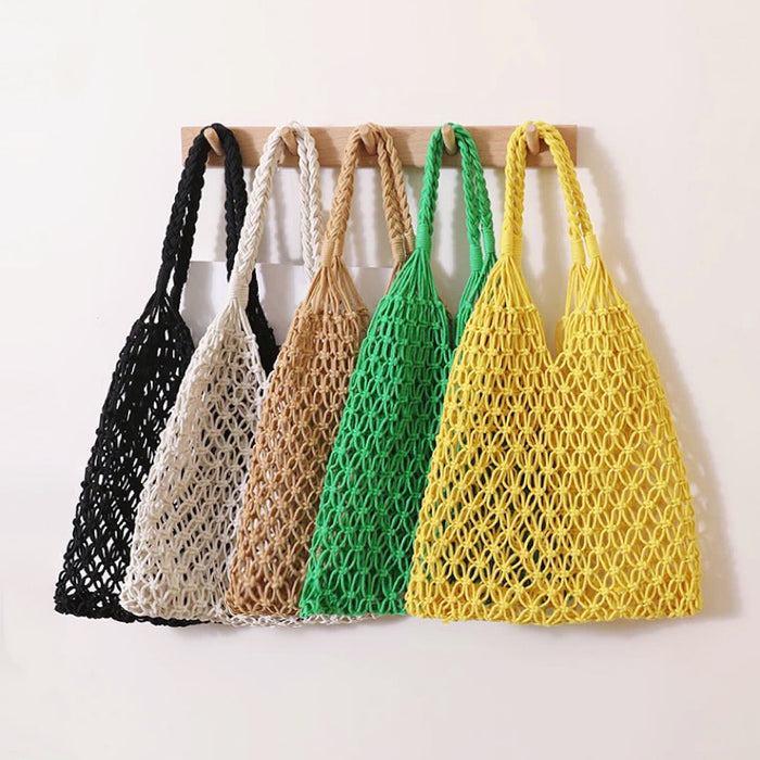 Front view of Five cotton rope hollow crochet tote bags in black, white, tan, green, and yellow hanging on a wooden.