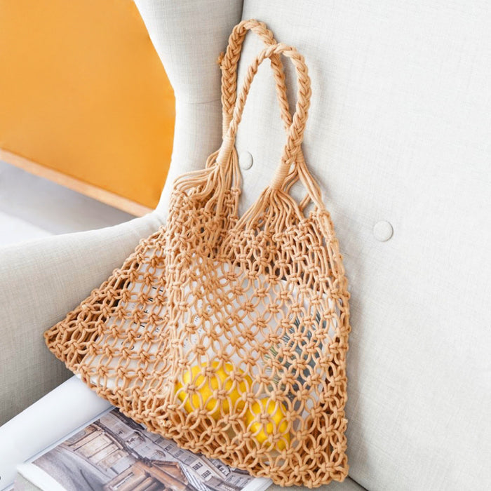 Close-up of Tan hollow crochet tote bag made from cotton rope with braided handles in camel.