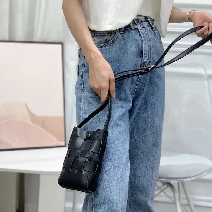 Model carrying a black Hollow Design Woven Leather Crossbody Bag handheld, ideal for city walks and gifting.