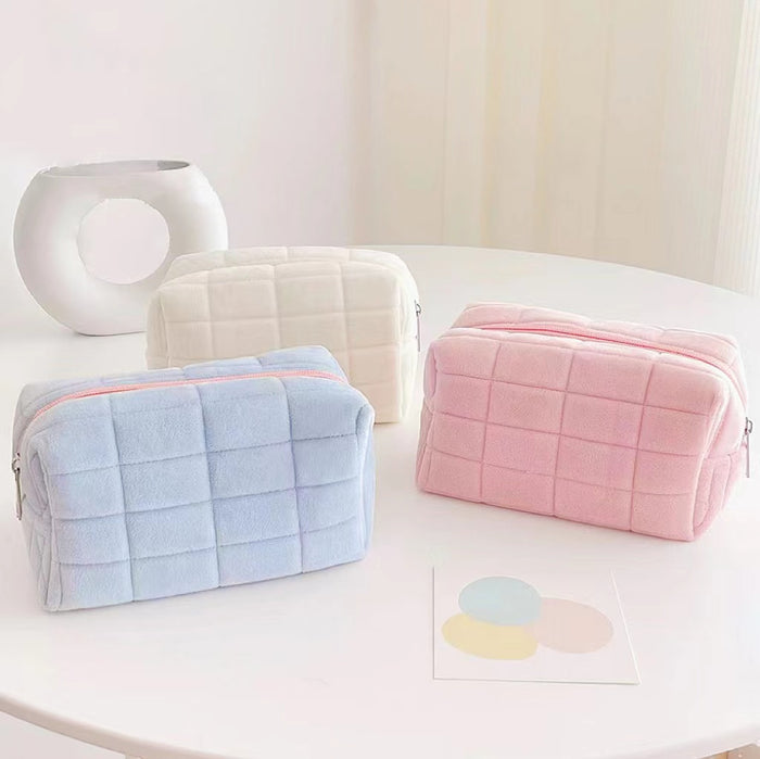 Front view of Three soft flannelette makeup bags in pastel pink, blue, and white, with a quilted texture and zipper.