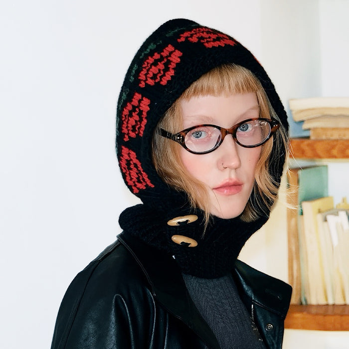 Black jacquard knitted balaclava with red floral pattern and wooden buttons for a stylish, cozy aesthetic.