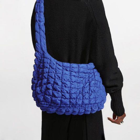 Back view of a model wearing the bright blue puffy crossbody bag.