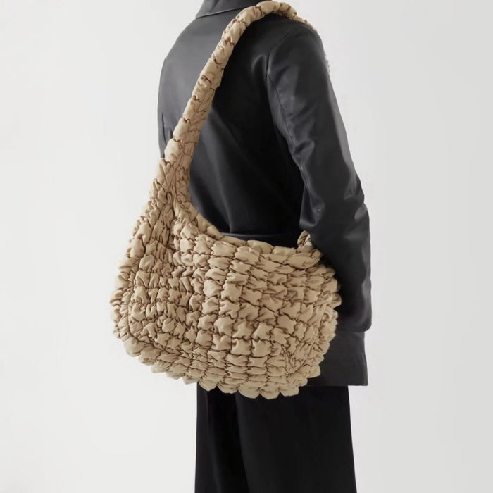 Side view of a model wearing the beige puffy crossbody bag.