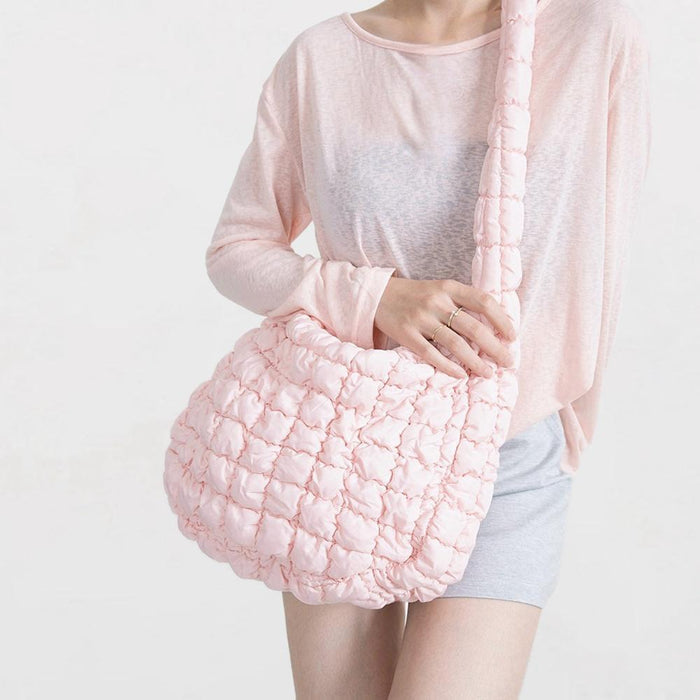 Model wearing the soft pink puffy crossbody bag with a light top.