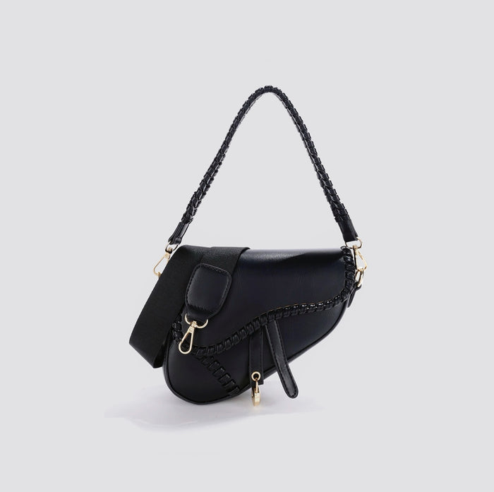 Angled view of Black PU leather saddle bag with braided top handle, removable shoulder strap, and decorative.