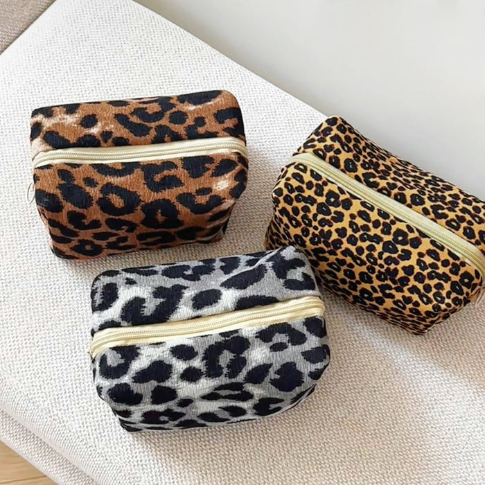 Front view of Three corduroy leopard print makeup bags: brown, tan, and gray, with gold zip-top fastenings makeup bag.