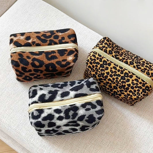 Front view of Three corduroy leopard print makeup bags: brown, tan, and gray, with gold zip-top fastenings makeup bag.