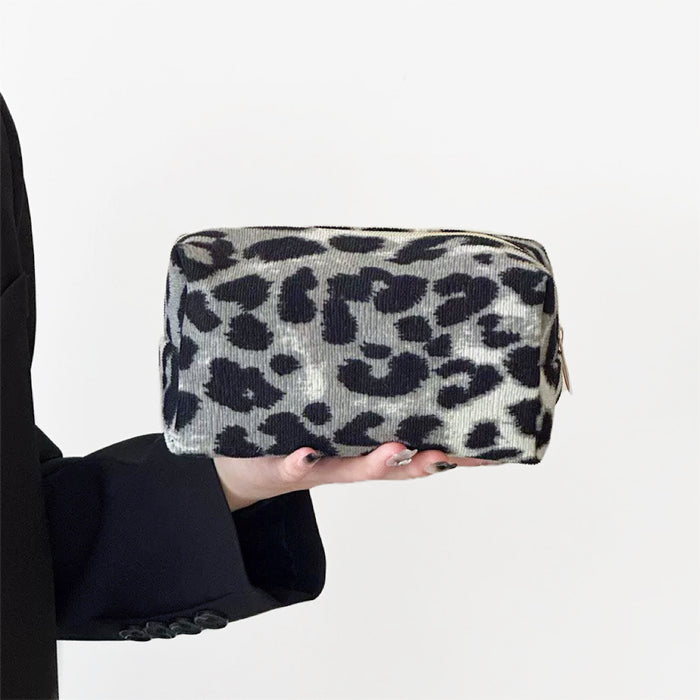 Model holding a gray leopard print makeup bag in hand, great for on-the-go touch-ups.