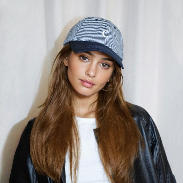 Woman wearing a blue and white Mash Up Stripe C Cap, a breathable cotton baseball cap for active outdoor styling.