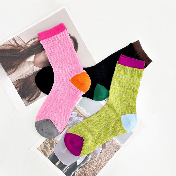 Angled view of Three pairs of colorful mesh gauze socks: pink with orange heel, black with green heel, and lime green.