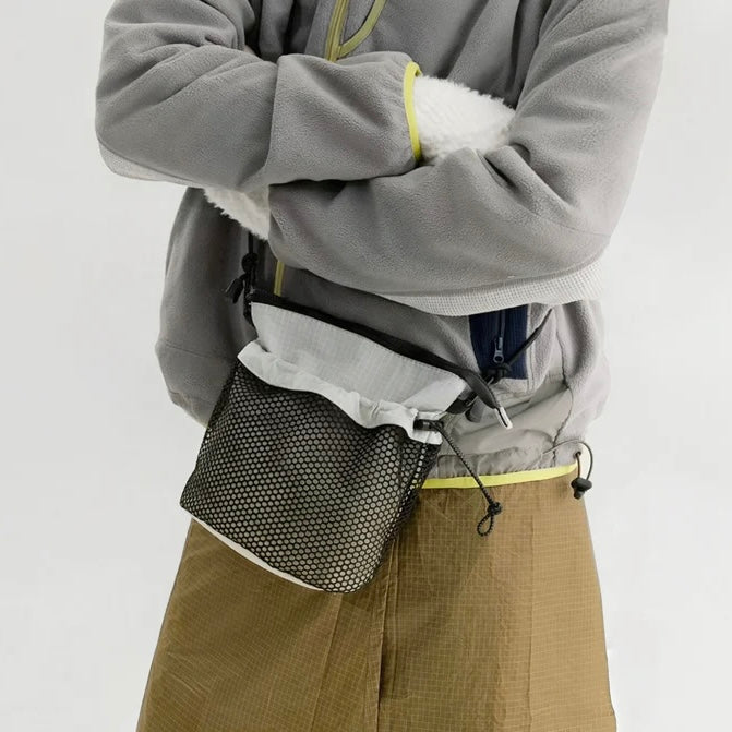 Model carrying a gray nylon crossbody bag as crossbody, great for daily carry and travel.