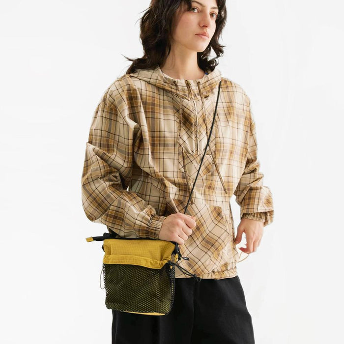 Model carrying a khaki nylon crossbody bag handheld, ideal for city walks and gifting.