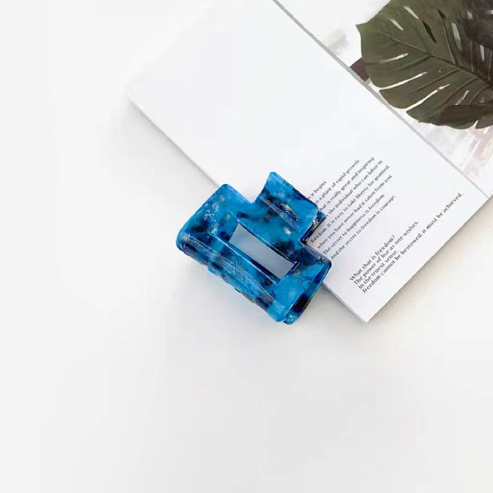 Angled view of blue Midnight Ice Hair Claw in cube shape , ideal for quick updos and ponytails.