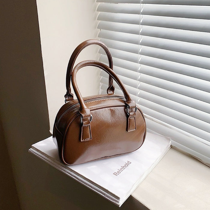 Angled view of Mini Leather Bowling Bag in brown, great for everyday carry and travel.