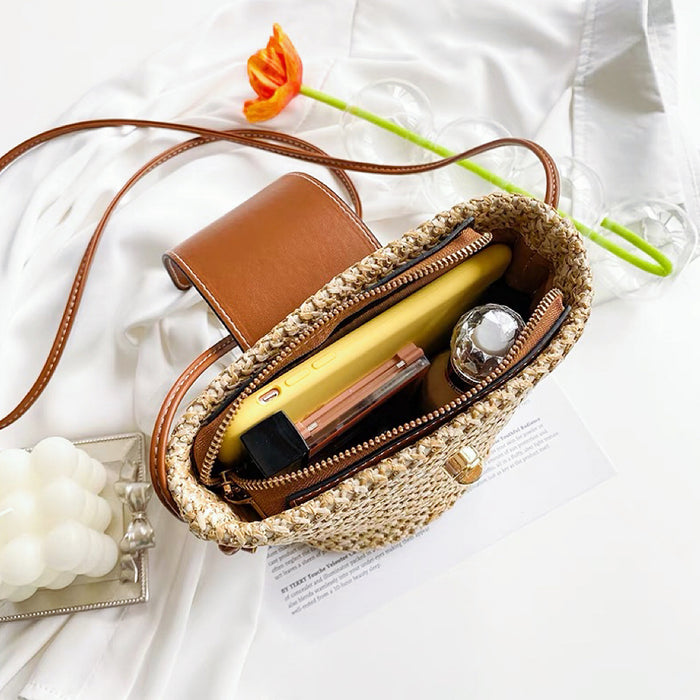 Angled view of Open mini raffia straw  bucket crossbody bag with phone and cosmetics inside